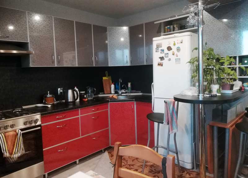 Угловой кухонный гарнитур с серо-красными фасадами и черной столешницей